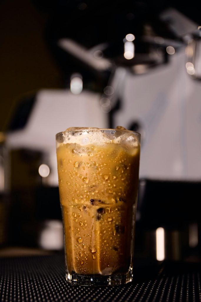 Close-up of a cold iced coffee with foam in a cafe setting. Perfectly lit and inviting.