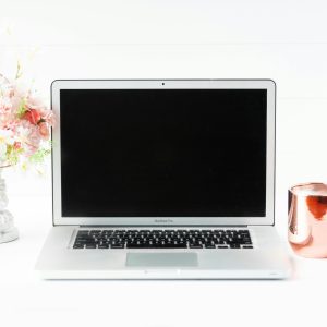 A sleek workspace featuring a laptop, floral arrangement, and copper mug for a modern aesthetic.